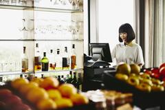 Woman standing behind a cash register.