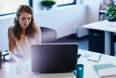 woman sitting at a desk behind a laptop woman sitting at a desk behind a laptop