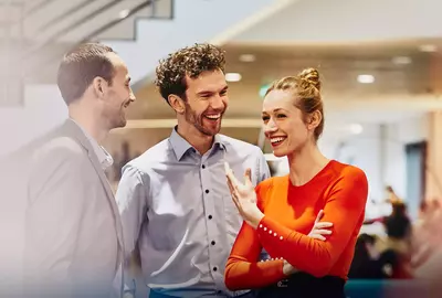 2 males and female standing and laughing
