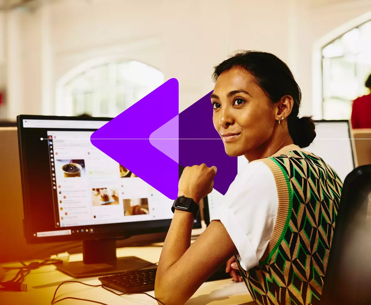 smiling female sitting in front of her computer, looking away