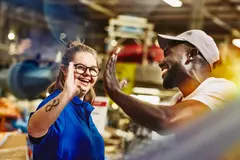male and female giving each other a high five in a warehouse.